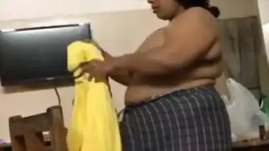 Fat Indian woman with big belly walks around the house with naked boobs